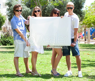 Teens with white billboard standing in park