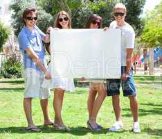 Teens with white billboard standing in park