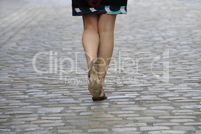 Woman walking on cobbled pavement