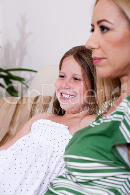 Mother and daughter sitting together on couch