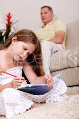 Cute girl studying with her father in the background