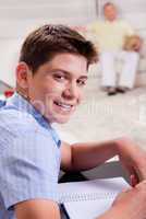 Young boy in focus, studying and smiling at camera