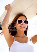 Smiling beach woman holding surfboard on her head