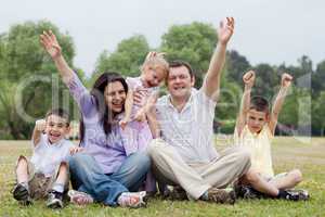 Happy family of five having fun by raising hands