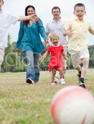 Sportive family playing football on the green lawn