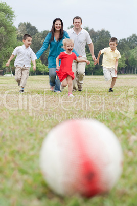Happy family of five having outdoors and playing soccer