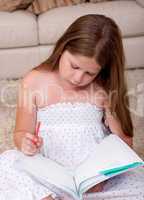 Young school girl reading book in living room