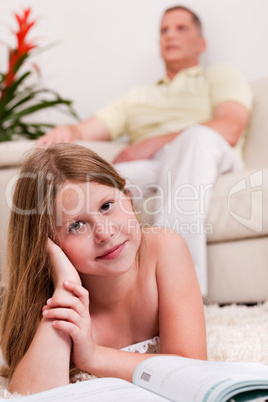 Young little girl lying with her book in living room