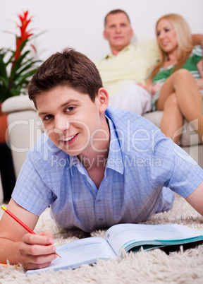 Smiling young boy lying with book in living room