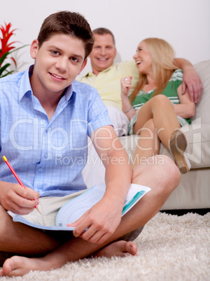 Young smiling teenager sitting with his book in living room