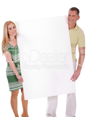 Middle aged smiling couple holding a blank white board