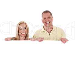 Middle aged couple standing behind a blank white board and smiling
