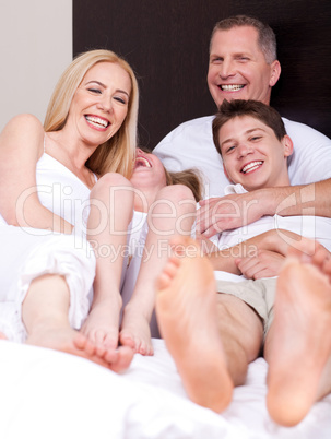 Loving family of four having fun and looking at you