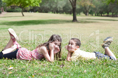 Cute children lie down on green grass