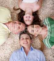 Happy family lying  with their heads close together smiling