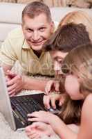 Happy family lying and working with lap top