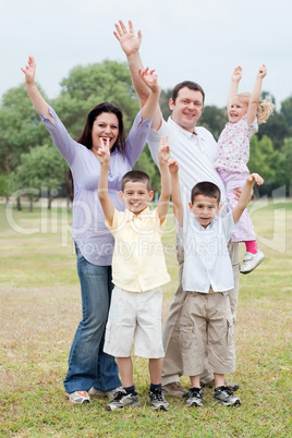 Happy family on outdoors  enjoying by raising hands