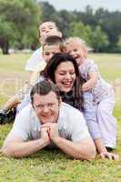 Happy family piled up  on the park and looking at you