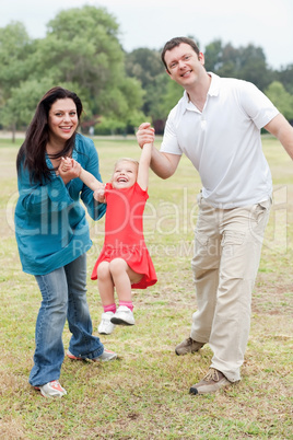 Lovely couples playing with their happy daughter at the park