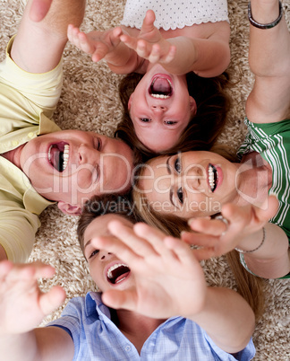 Happy family of four lying on the carpet