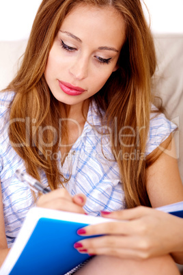 Busy woman sitting on sofa writing in notepad