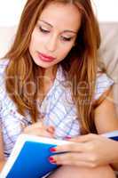 Busy woman sitting on sofa writing in notepad