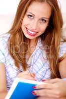 Young woman sitting on sofa writing in notepad