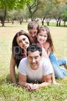 Happy family lying in the grass field at the park