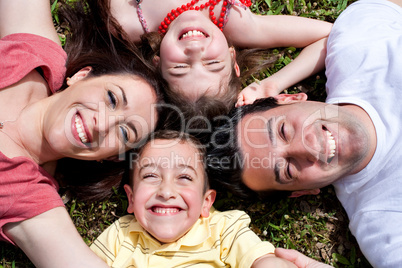 Happy family laying in the circle on green grass