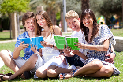 Smiling young couple holding books posing to camera