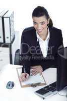 Business woman making notes and looking at the camera up