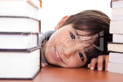 Happy young school boy surrounded by books