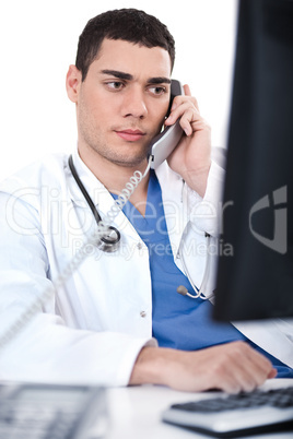 Portrait of male physician holding receiver and looking the computer