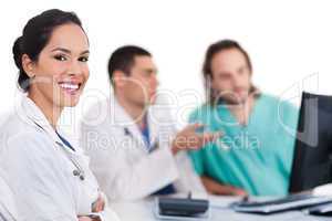 Smiling young doctor with other doctors behind her
