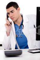 Caucasian male doctor sitting at the desk with computer talking over phone