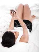 Sexy woman in bed looking in her mobile