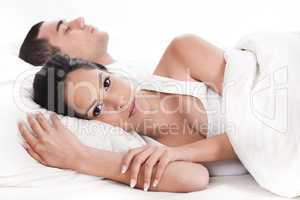 Couple in bed, men sleeping and woman lying sleepless