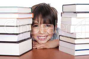 Happy young school boy surrounded by books
