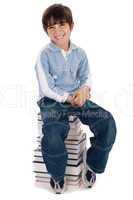 Smiling young kid sitting over pile of books