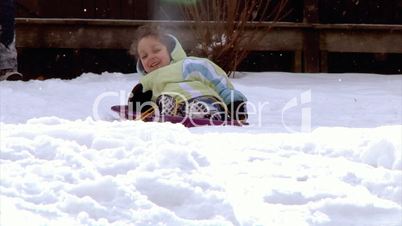 A little girl goes sled ridding.  Slow motion