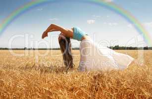 stretching woman in the meadow with rainbow
