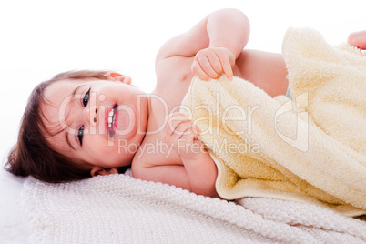 Little smiling baby lying in white towel and wrapped with yellow