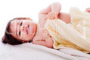 Little smiling baby lying in white towel and wrapped with yellow