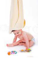 Baby with towel on is head while playing toys