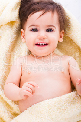 Cute baby smiling covered in yellow towel