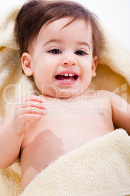 Portrait of a happy baby wrapped in yellow towel