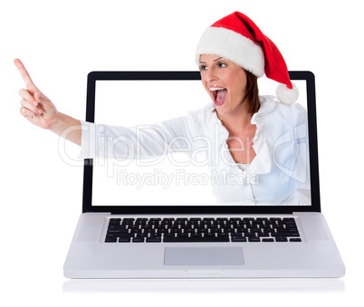 Young happy santa girl pointing up through the laptop screen