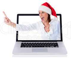 Young happy santa girl pointing up through the laptop screen