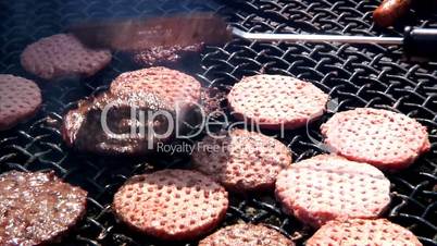 Flipping burgers on the grill.