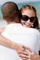 Portrait of pretty woman holding her husband while at beach